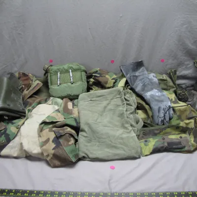 Sale Photo Thumbnail #105: Collection of vintage US military gear, including woodland camouflage jackets, canvas canteen pouch, rubber gloves, overshoes, and combat boots.