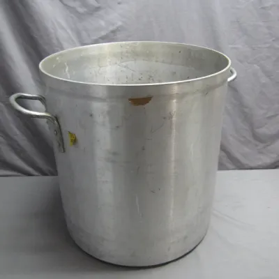 Sale Photo Thumbnail #27: Large commercial aluminum stockpot with dual riveted side handles, showing minor surface wear and adhesive residue.