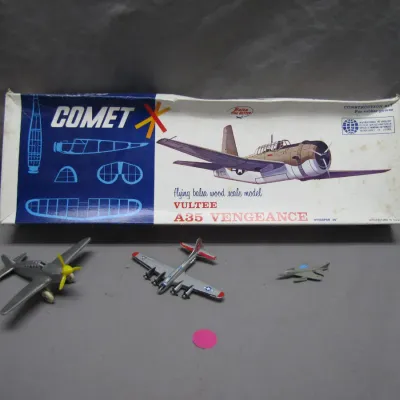 Sale Photo Thumbnail #114: Vintage Comet Vultee A35 Vengeance flying balsa wood scale model airplane kit in original box, displayed alongside three die-cast toy airplanes.
