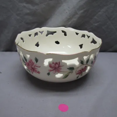Sale Photo Thumbnail #103: Vintage Lenox ceramic reticulated bowl featuring hand-painted pink floral motifs and a gilt rim.