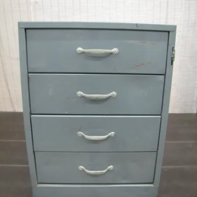 Sale Photo Thumbnail #56: Vintage gray metal four-drawer filing cabinet or storage organizer with silver bow-shaped handle pulls, showing light wear and scuffing.