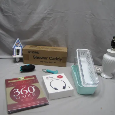 Sale Photo Thumbnail #252: Assortment of household items including a boxed shower caddy, white ceramic table lamp base, plastic organizer bins, Dealworthy wired headphones, and a copy of "The 360° Leader" by John C. Maxwell.