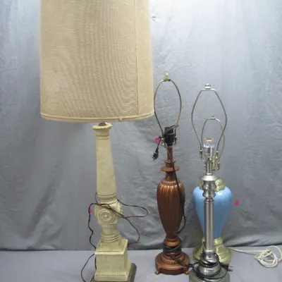 Sale Photo Thumbnail #200: Collection of four vintage table lamps, including a tall off-white painted column lamp with a drum shade, a turned wooden lamp, a silver-tone metal lamp, and a blue ceramic lamp base.