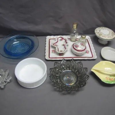 Sale Photo Thumbnail #88: Collection of vintage glassware and porcelain decorative items, including cobalt blue dishes, a floral vanity tray set, crystal lotus candle holder, milk glass bowl, and smoked glass dish.