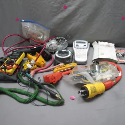 Sale Photo Thumbnail #214: Assorted lot of electrical tools and supplies, including a digital multimeter, label maker, trouble light, heavy-duty power cords, and testing leads.