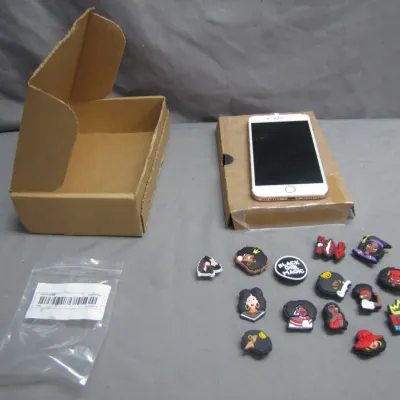 Sale Photo Thumbnail #80: Collection of Black Girl Magic themed shoe charms displayed alongside an empty cardboard box, plastic bag, and a smartphone resting on packaging.