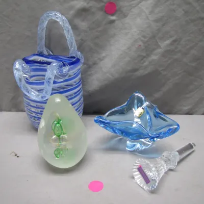 Sale Photo Thumbnail #98: Collection of decorative art glass items, including a blue and white striped basket-form vase, an egg-shaped paperweight, a light blue folded bowl, and a cut glass bottle stopper.
