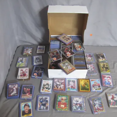 Sale Photo Thumbnail #33: Collection of sports trading cards, including football and baseball cards from various eras, housed in protective sleeves and a white storage box.
