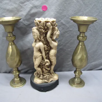 Sale Photo Thumbnail #108: Carved faux-ivory Indian maiden candle holder flanked by a pair of brass pillar candlesticks.