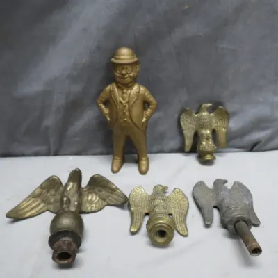 Sale Photo Thumbnail #16: Collection of five vintage brass and metal decorative items, including four eagle flag pole toppers and a small figurine of a man in a bowler hat.