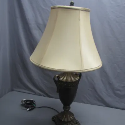 Sale Photo Thumbnail #132: Classic urn-style table lamp with a dark bronze and brass finish, paired with a soft cream flared shade.