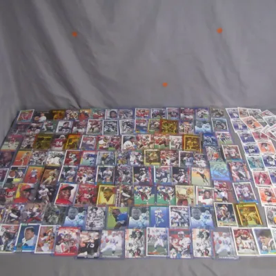 Sale Photo Thumbnail #12: Large collection of vintage football trading cards featuring various players and sets, mostly from the 1980s and 1990s, presented in protective sleeves and loose piles.