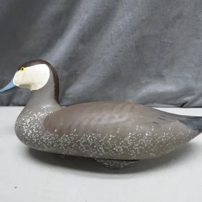 Sale Photo Thumbnail #5: Hand-carved and painted wooden duck decoy featuring detailed plumage, a white-cheeked face, and yellow glass eyes.