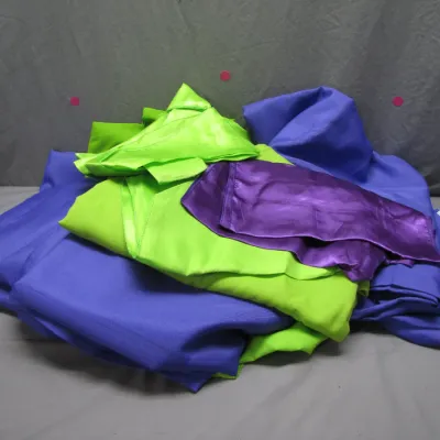 Sale Photo Thumbnail #75: Pile of colorful fabric remnants in shades of lime green, purple, and blue satin and woven textiles.