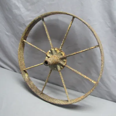 Sale Photo Thumbnail #174: Vintage spoked cast iron wagon wheel with heavy rust patina and trace remnants of yellow paint.