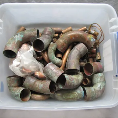 Sale Photo Thumbnail #120: Plastic tote filled with assorted scrap copper plumbing pipe fittings and elbows showing heavy oxidation.
