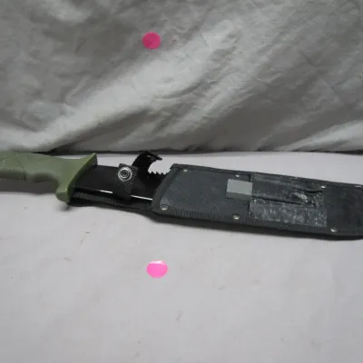 Sale Photo Thumbnail #66: Tactical survival knife featuring an olive green composite handle, partially serrated black blade, and black nylon sheath with a built-in sharpening stone pocket.