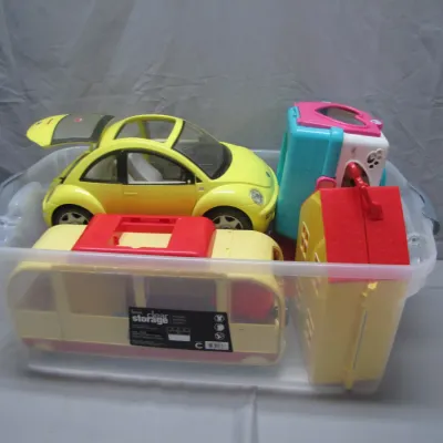 Sale Photo Thumbnail #46: Clear plastic storage tub filled with various vintage plastic toys, including a yellow Volkswagen Beetle car and playhouses.