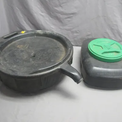 Sale Photo Thumbnail #170: Two black plastic automotive oil drain pans, including one with a pour spout and one with a green screw-on cap.