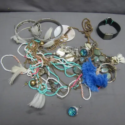 Sale Photo Thumbnail #271: Collection of assorted costume jewelry including beaded necklaces, feather details, metal bangles, and a blue tassel accent.