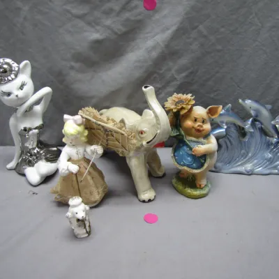 Sale Photo Thumbnail #112: Collection of vintage porcelain figurines, including a glamorous white and silver cat, an elephant, a girl with an umbrella, a pig holding a sunflower, and jumping dolphins.
