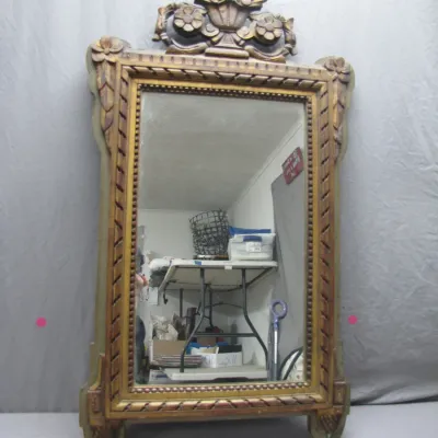Sale Photo Thumbnail #205: Vintage ornate gilded wood wall mirror featuring a carved floral urn crest and decorative corner details.