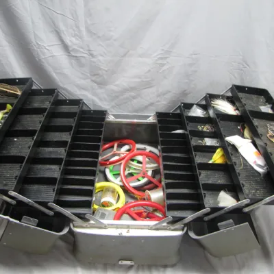 Sale Photo Thumbnail #53: Vintage metal cantilever tackle box filled with an assortment of fishing lures, line wheels, and terminal tackle.