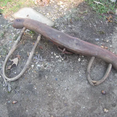 Sale Photo Thumbnail #143: Antique rustic double ox yoke made of carved wood with bentwood bows, showing heavy wear and weathering from age.