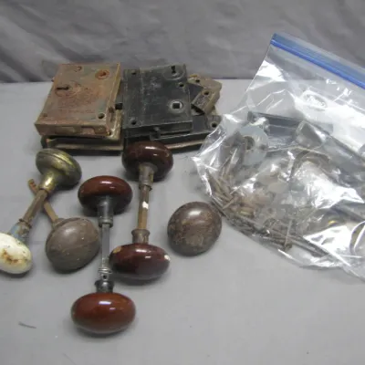 Sale Photo Thumbnail #179: Collection of antique hardware, including porcelain and metal door knobs, cast iron rim lock assemblies, and a bag of assorted screws and strike plates.
