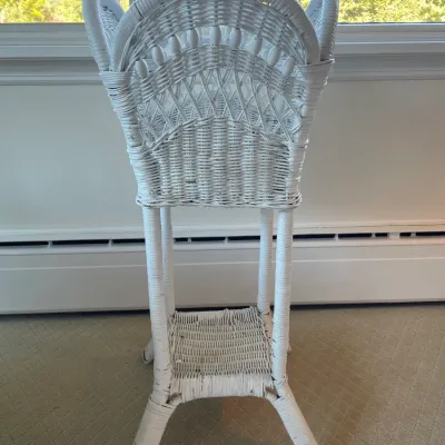 Sale Photo Thumbnail #54: Vintage white-painted wicker plant stand featuring a woven basin top, lower display shelf, and decorative spindle accents.