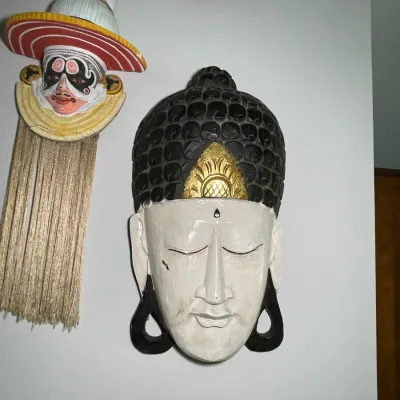 Sale Photo Thumbnail #69: Collection of decorative Asian wall masks, featuring a carved wooden Buddha head and a hand-painted Kathakali mask with fringe trim.