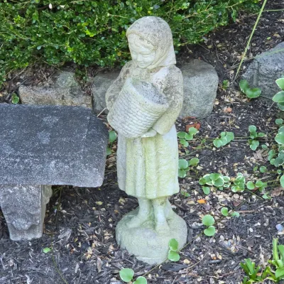 Sale Photo Thumbnail #50: Weathered concrete garden statue depicting a young girl in a headscarf holding a woven basket.