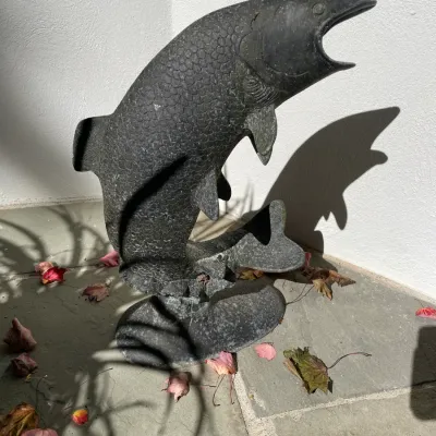 Sale Photo Thumbnail #26: Weathered bronze or stone garden sculpture depicting a leap salmon, featuring detailed scale textures and a rounded base.