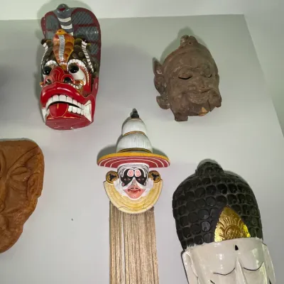 Sale Photo Thumbnail #71: Collection of decorative wall-hanging masks, including hand-carved Sri Lankan cobra masks, Kathakali figures, and Asian deity faces.