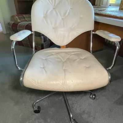 Sale Photo Thumbnail #67: Vintage mid-century modern swivel desk chair featuring tufted cream vinyl upholstery and a chrome frame with rolling casters.
