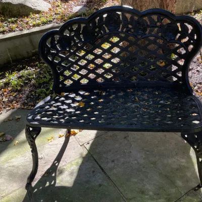 Sale Photo Thumbnail #18: Black cast aluminum outdoor garden bench with rose motif backrest and crosshatch seat pattern.