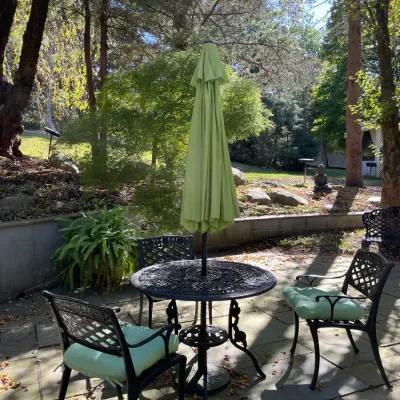 Sale Photo Thumbnail #15: Black cast aluminum patio set with a round table, green market umbrella, and matching armchairs featuring mint green seat cushions.