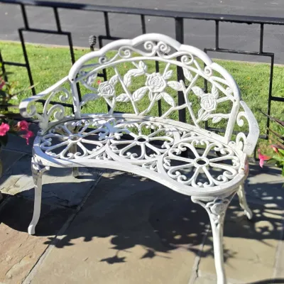 Sale Photo Thumbnail #47: White painted cast aluminum vintage garden bench featuring a rose motif backrest and scrollwork details.