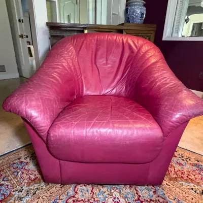 Sale Photo Thumbnail #28: Vintage magenta leather accent armchair featuring a deep barrel seat and wide, rounded arms. The leather displays light distressing and creasing consistent with age and use.