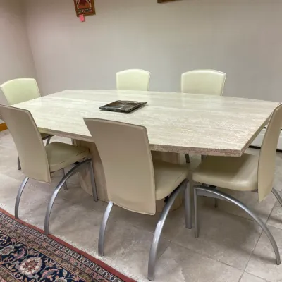 Sale Photo Thumbnail #2: Contemporary dining set featuring a large travertine stone top table paired with six modern beige upholstered chairs with silver curved metal legs.