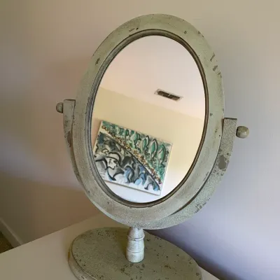 Sale Photo Thumbnail #64: Vintage oval tabletop vanity mirror featuring a distressed sage green crackle finish and swivel stand.