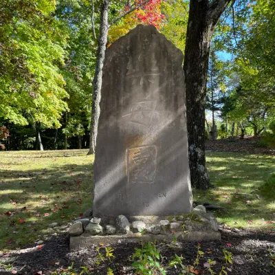 Sale Photo Thumbnail #22: Large carved stone garden monument featuring Chinese characters, dated 1915 and marked 'Raku-Bo-Yen', set outdoors in a wooded landscape.