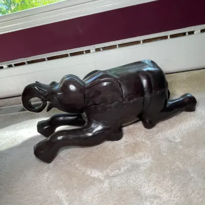 Sale Photo Thumbnail #32: Carved dark wood elephant figurine depicted in a reclining position, featuring a smooth, polished finish.