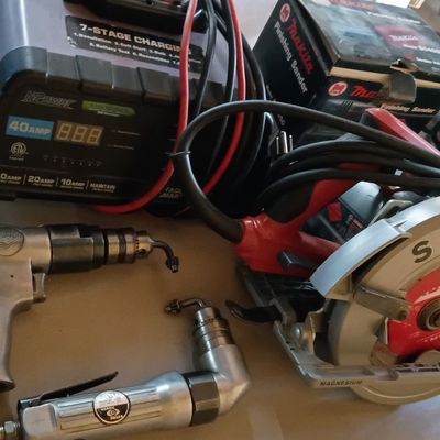 Collection of power tools including a Skilsaw magnesium circular saw, NPower 40-amp battery charger, pneumatic drills, and a boxed Makita...