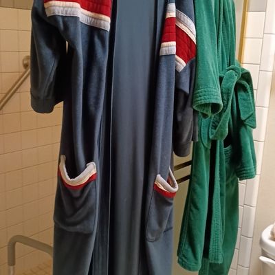 Vintage blue velour bath robe with red and white athletic striping details hanging alongside a green terry cloth robe.