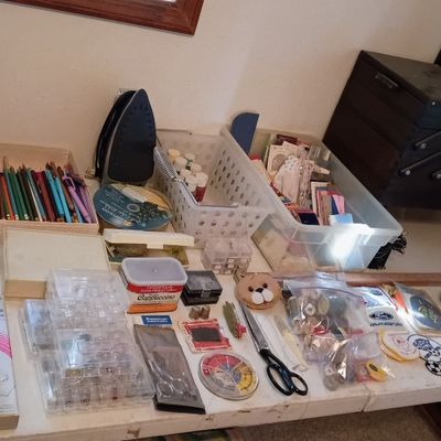 A large assortment of crafting and sewing supplies, including paintbrushes, colored pencils, thread, scissors, bobbins, patches, an iron,...