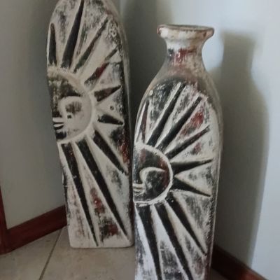 Pair of rustic ceramic floor vases featuring carved celestial sun motifs with a distressed whitewash finish.