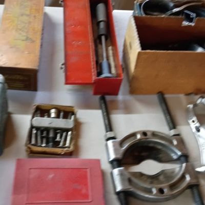 Collection of vintage hand tools and hardware, including gear pullers, bearing splitters, a socket set, and various metal and wooden...