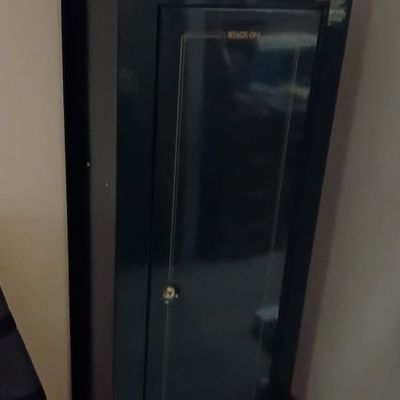 Black Stack-On tall steel security safe cabinet topped with a small vintage portable radio.