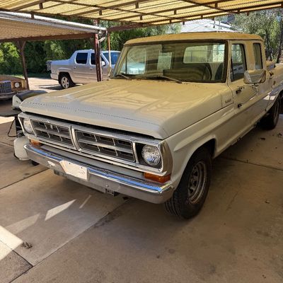 Vintage white Ford F-series crew cab pickup truck parked under a covered carport.